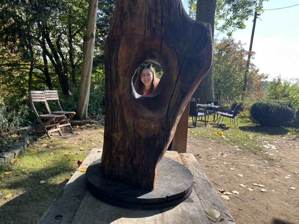 Paula schaut zufrieden auf/durch ihre Skulptur